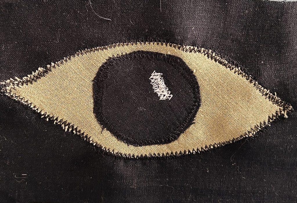 green and black fabric eye applique on black fabric